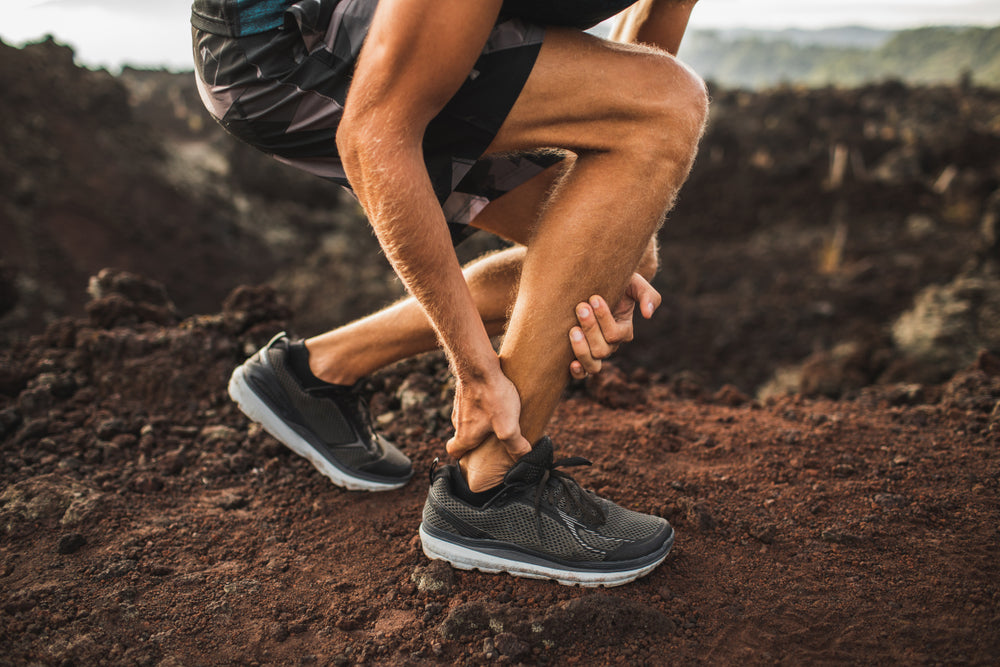 Man in pain with heel spurs in running shoes on a dirt path